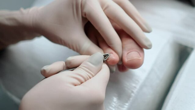 A pedicure master does cleaning and massage, pedicure, to a young beautiful girl with a small foot. Caring for female beauty in a beauty salon during a procedure. Skin of feet and toes close-up