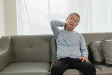 Asian elderly man has back pain and sickness in bed at home, unhappy elderly man touching his back...