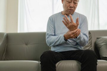 An elderly Asian male patient suffers from pain and numbness in his hand from rheumatoid arthritis....