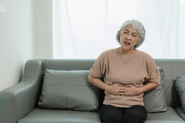 An elderly woman has severe abdominal pain. Sitting alone on the sofa while having dinner at home,...