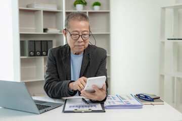 Asian senior businessman working at office with documents on table Planning to analyze financial reports business plan investment financial analysis concepts Use a calculator