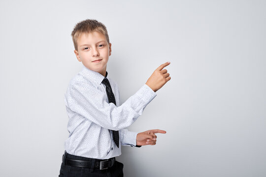 Portrait boy in school uniform pointing with finger at empty space for product advertising or text