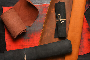 Multicolor leather rolled up pieces scrolls on the black table background. Top view.