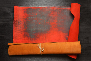 Brown and red leather rolled up pieces scrolls on the black table background with copy space. Top...
