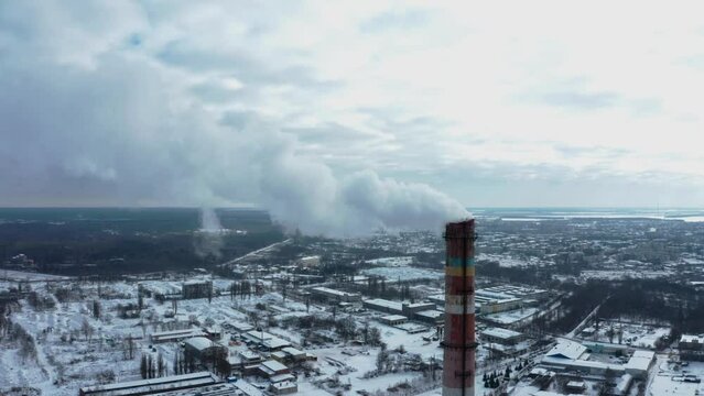 Drone flying around a smoking chimney, close-up. Pollution of the atmosphere by an industrial enterprise of the TPS station.  Smog smoke carbon and pollution emissions from industry smokestacks.