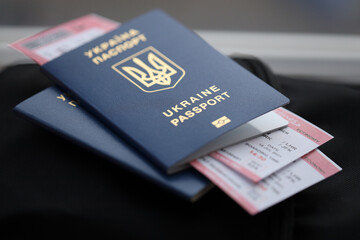 Two ukrainian biometrical passports with air flight tickets on black touristic backpack close up