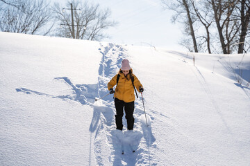 A figure in a yellow jacket snowshoeing down a snowy slope