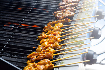 Asian cuisine, Malaysia chicken satay cooking on a hot charcoal grill.