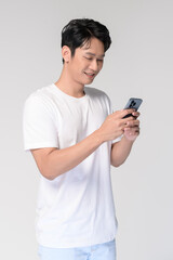Portrait of young smiling asian man using smartphone over white background