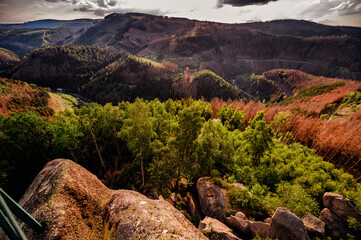 The setting sun casts a warm glow over forested hills, viewed from a high vantage point, evoking a...