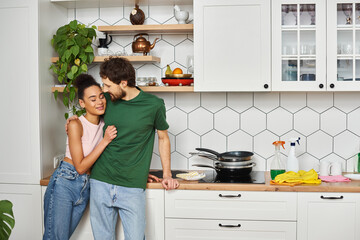 beautiful cheerful diverse couple in cozy homewear enjoying each other and smiling happily