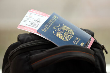 Blue United Arab Emirates passport with airline tickets on touristic backpack close up. Tourism and...