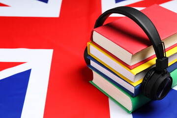 Learning foreign language. Different books and headphones on flag of United Kingdom, space for text