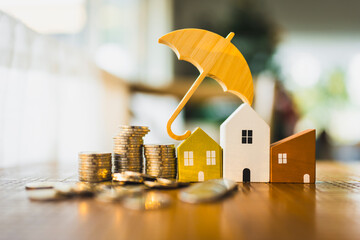 A picture of a house model and a pile of money with a umbrella symbol on top, a concept related to...