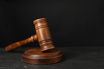 Wooden gavel on dark textured table, closeup. Space for text