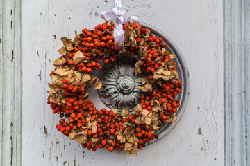 A circle of flowers as a decoration hanging on a door outdoors