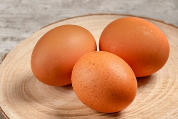 Close-up of brown, brown eggs on wooden board and background.