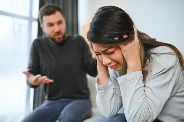 Emotional man gesturing and shouting at his wife, young couple having quarrel at home. Domestic abuse concept