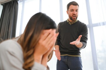 An agitated and upset husband shouts and looks at his wife, a quarrel between spouses. Family misunderstanding, quarrel