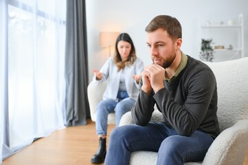 Family quarrel, man and woman sitting on sofa at home. angry woman yells at her husband