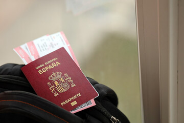 Red Spanish passport of European Union with airline tickets on touristic backpack close up. Tourism and travel concept