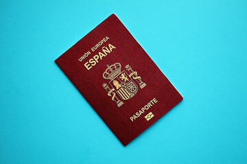 Red Spanish passport of European Union on blue background close up. Tourism and citizenship concept