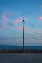 Light post shining on the Vencie Pier during dusk.