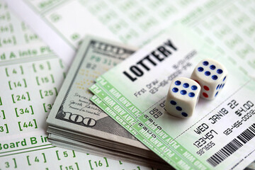 Green lottery tickets and US money bills on blank with numbers for playing lottery close up