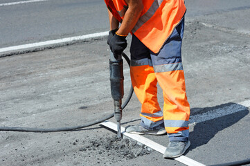 Worker preparing lay for asphalting the road on the street using pneumatic road breaker