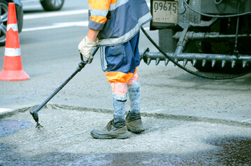 worker spraying bitumen repairing the road, oil tar spreader truck