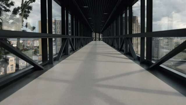 empty walkway, glass pathway, skybridge features. Contemporary, glass-walled skybridge with metallic infrastructure, connecting pair buildings, vacant, amid lockdown.