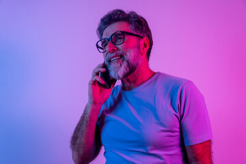 Pleasant news. Portrait of happy excited man joyfully looking at phone screen isolated over neon...