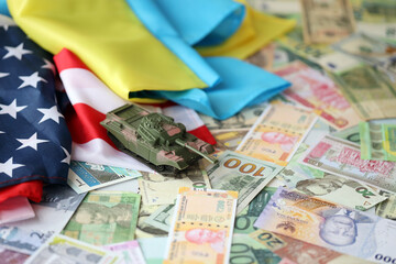Toy tank on US flag and ukrainian flag on many banknotes of different currency. Background of war...