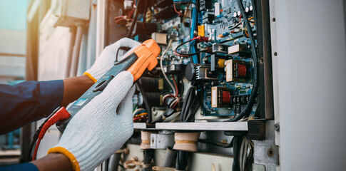 Technician is checking air conditioner refrigerant system maintenance and check switch board control