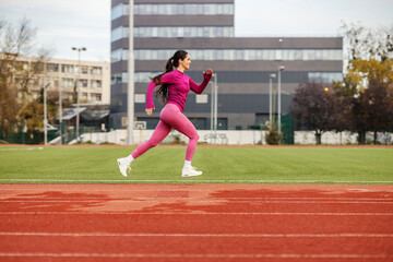 Obraz premium A fast female athlete in shape is jumping and running at stadium.