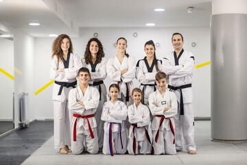 Portrait of taekwondo girls and boys posing in martial art school with their trainer.