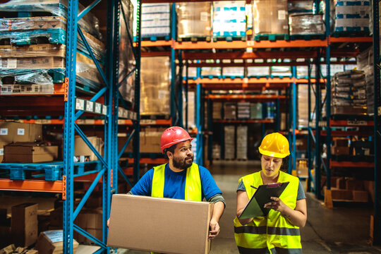 Workers in safety gear checking inventory in warehouse