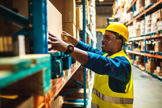 Young male warehouse worker carrying a box