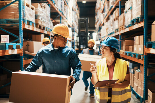 Workers in safety gear checking inventory in warehouse