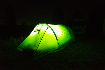 a lit up tent pitched in the dark in the field