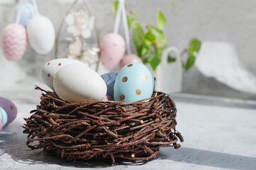 Spring still life with colored eggs. Easter bunny and eggs with a delicate color pattern in a nest. Easter decor in the house
