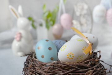 Spring still life with colored eggs. Easter bunny and eggs with a delicate color pattern in a nest. Easter decor in the house.