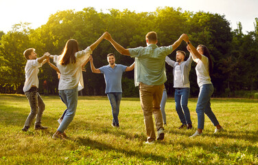 Group of happy casual friends have fun in summertime, enjoy summer weekend in green park, have good...