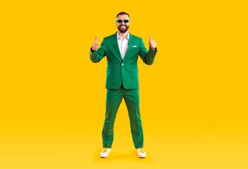 Full body length shot of happy confident handsome bearded young man in trendy funky green suit and...