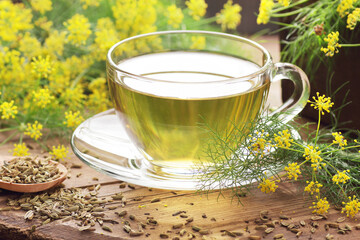Fennel seed tea or extract on wooden background with fresh flowers nearby, copy space, natural...