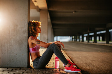 Young woman taking a break from jogging and exercising in a parking lot