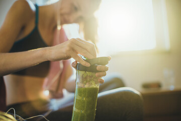 Young woman having a post workout smoothie shake at home in the morning