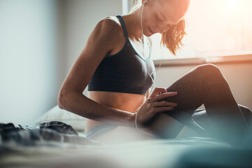 Young woman getting ready at home to go exercise and jog outside in the morning - obrazy, fototapety, plakaty