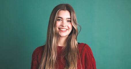 Happy woman with long blonde hair smiling in green studio