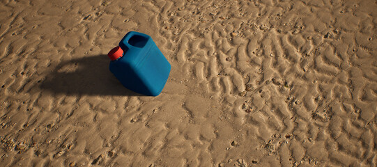Plastic blue container with red cap lying in rippled sand of beach. - 746726064